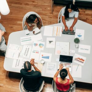 A top-down view of colleagues seated at a table reviewing presentation slides.