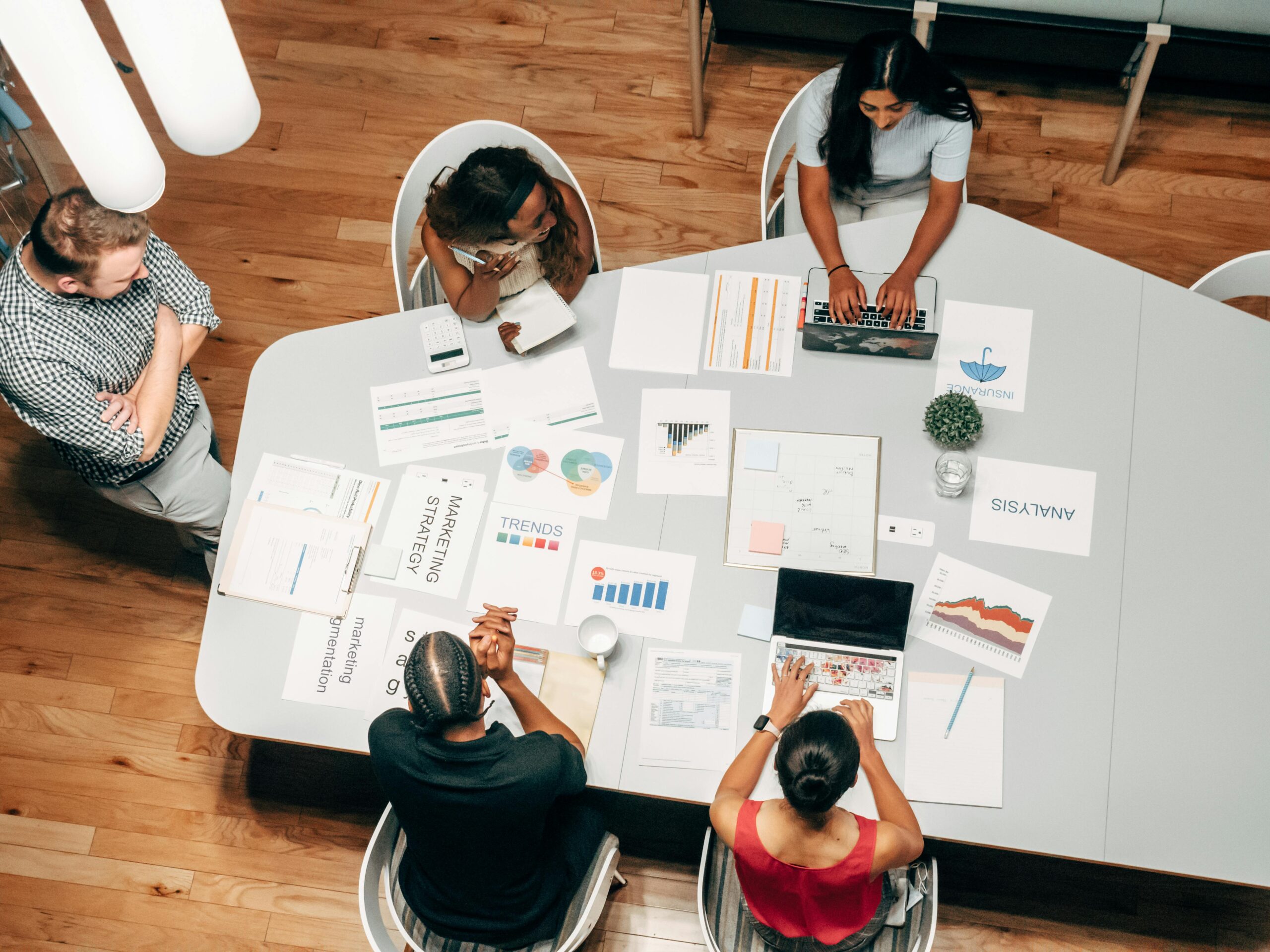 A top-down view of colleagues seated at a table reviewing presentation slides.
