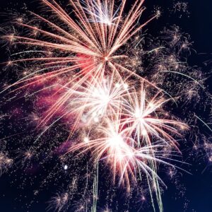 Spectacular fireworks exploding in vivid reds, golds, and blues against a deep night sky, creating a dramatic celebration scene.